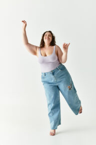 Joyful young woman showcasing her fashionable style while dancing in a vibrant setting.